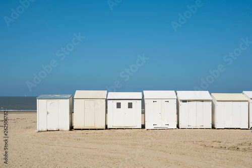 row white beach houses, cabines in Blankenberg, Belgium, against blue sky. Space for text