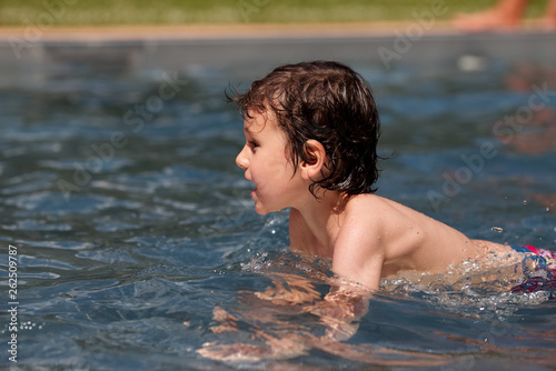 Little boy having fun in the pool in summer day. Childhood and family concept.