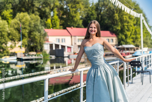 Young beautiful woman in dress standing on pier © RomanR