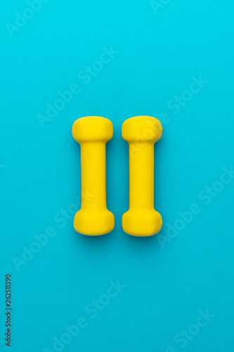 photo of yellow fitness dumbells over blue backgound with central composition