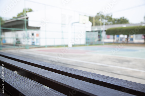 empty old wooden bleachers with blurred basketball court background.