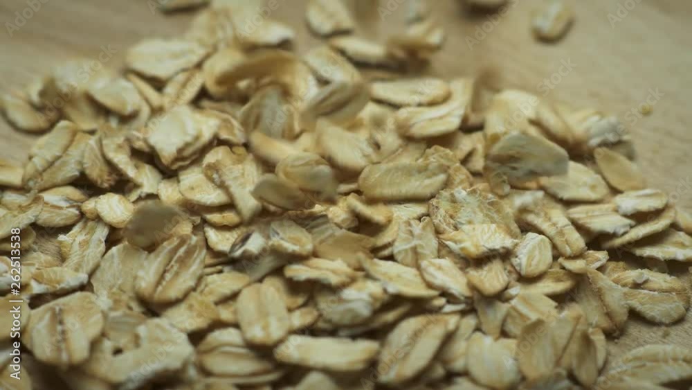 Oatmeal falls on the wooden rotating board; close up, macro shot. Oatmeal falls on the wooden rotating board; close up, macro shot.