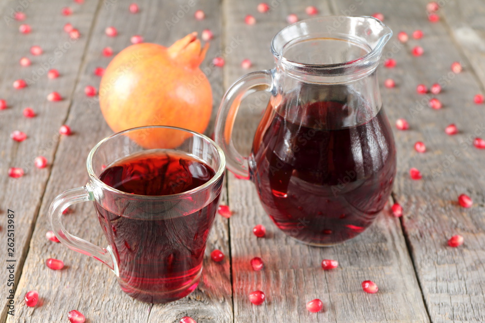 A mug of pomegranate juice on a grey wooden background. A mug of pomegranate juice on a grey wooden background.