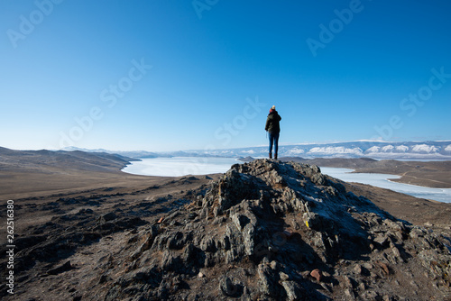 Landscape of women tourists standing on the rocky mountain and frozen Baikal lake view in Russia