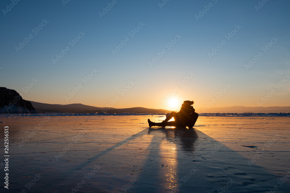 Silhouette photo of happy woman is sit and kiss the sun on ice
