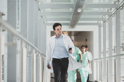 Doctor using pager in hospital corridor photo