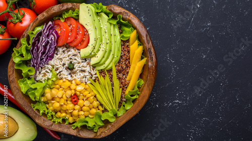 Healthy vegan superfood bowl with quinoa, wild rice, chickpea, tomatoes, avocado, greens, cabbage, lettuce on black stone background top view with copy space. Food and health