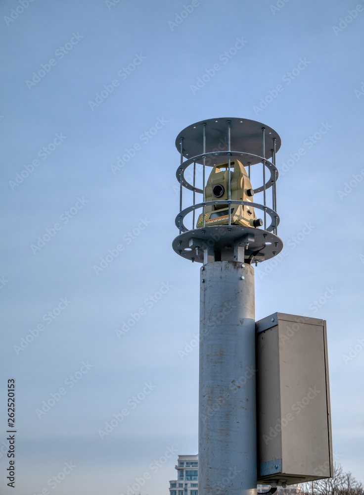 modern theodolite geodesy equipment in security cage on tall column