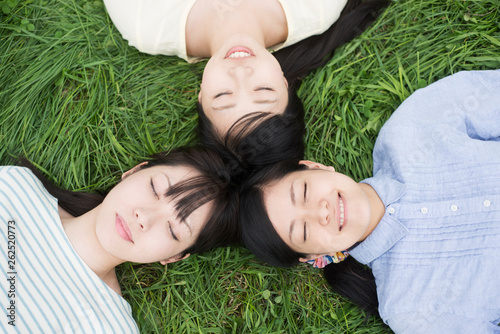 草原に寝転ぶ3人の女性