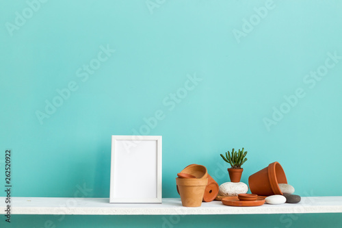 White shelf against pastel turquoise wall with pottery and succulent plant.