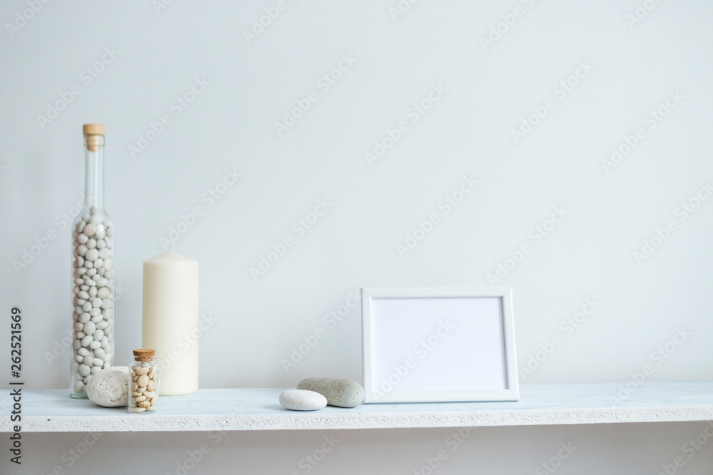 Shelf against white wall with decorative candle, glass and rocks. Shelf against white wall with decorative candle, glass and rocks.