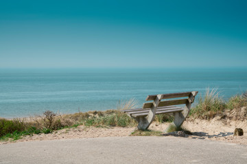 Foto auf Acrylglas Nordsee Dünenlandschaft mit Bank am Strand Burgh Haamstede, Niederlande. Nordseeküste. Blauer Himmel, Platz für Text  © Corinne