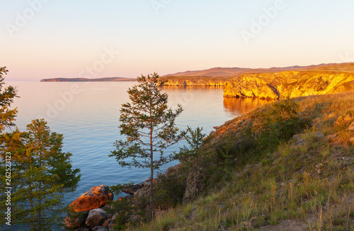Fototapeta Naklejka Na Ścianę i Meble -  Baikal Lake. Coast of Olkhon Island. Summer sunset colored coastal cliffs in golden color. Beautiful landscape. Natural background