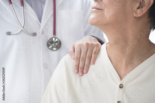 Medical doctor reassuring senior patient and putting a hand on patient’s shoulder