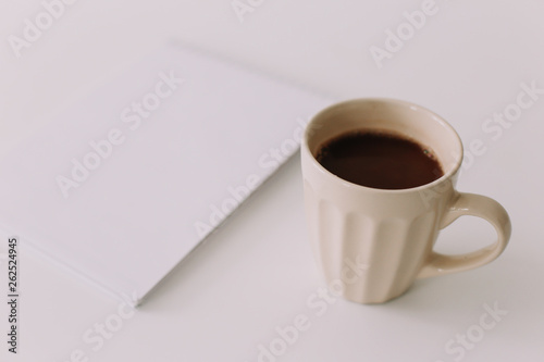 A coffee cup and a notebook. Business breakfast on white background. Flat lay, top view, office desktop 