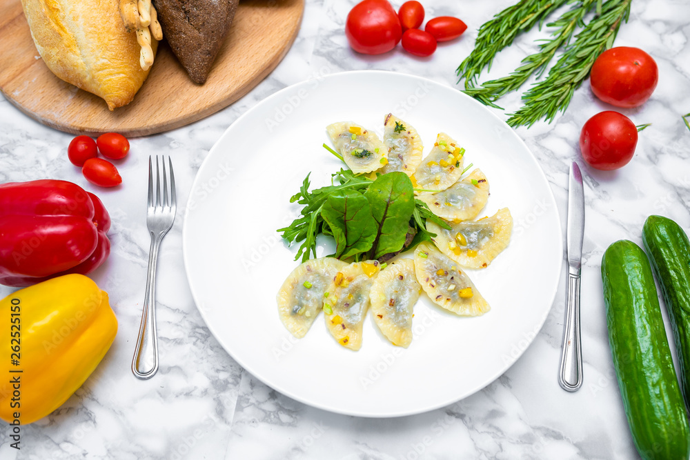 Dumplings, filled with cabbage. vegetable dumplings. Dumplings with potatoes in plate on white background. Ingredients for dumplings with cabbage, potatoes, tomato, cucumber, lettuce, pepper. Top vie Dumplings, filled with cabbage. vegetable dumplings. Dumplings with potatoes in plate on white background. Ingredients for dumplings with cabbage, potatoes, tomato, cucumber, lettuce, pepper. Top vie