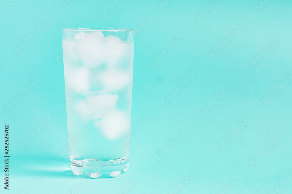 Close up of pure water with ice in tall transparent glass with copy space on blue background. Close up of pure water with ice in tall transparent glass with copy space on blue background.
