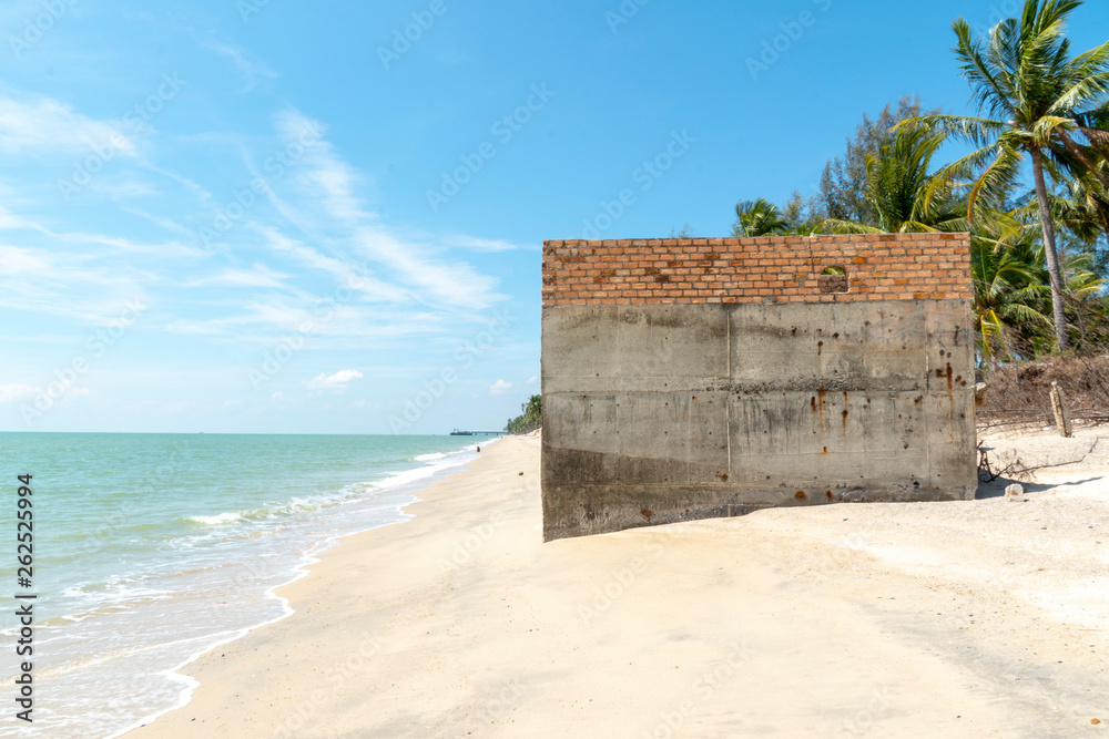 Abandoned of an old concrete orange brick wall on the tropical beach on sunny day with clear blue sky during summer time.