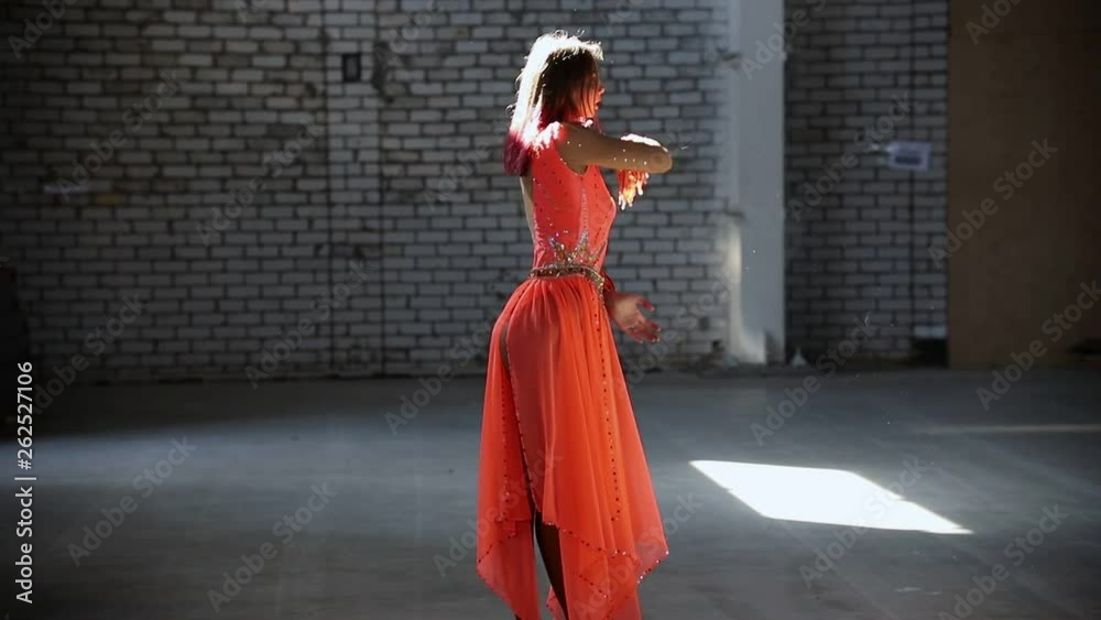 Young woman ballerina in orange dress making a gracefully performance Young woman ballerina in orange dress making a gracefully performance