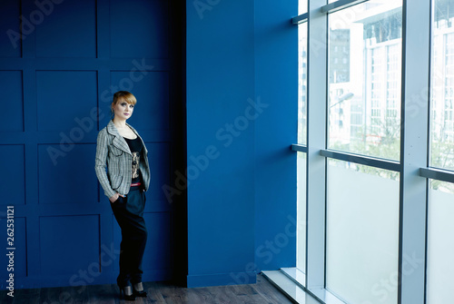 business girl in strict clothes standing near a wall with glasses