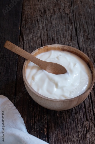 Natural homemade plain organic yogurt in wood bowl on wood texture background