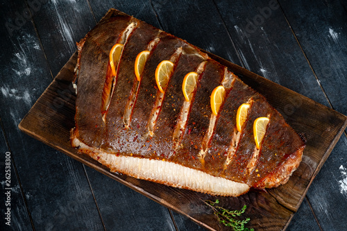 Fotografija Baked halibut fish with lemon homemade on a wooden Board on a dark background, s