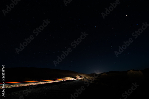 night photos on the Teide volcano in Tenerife. Images of the starry sky at night with the glow of the cities on the horizon and light trail of a car
