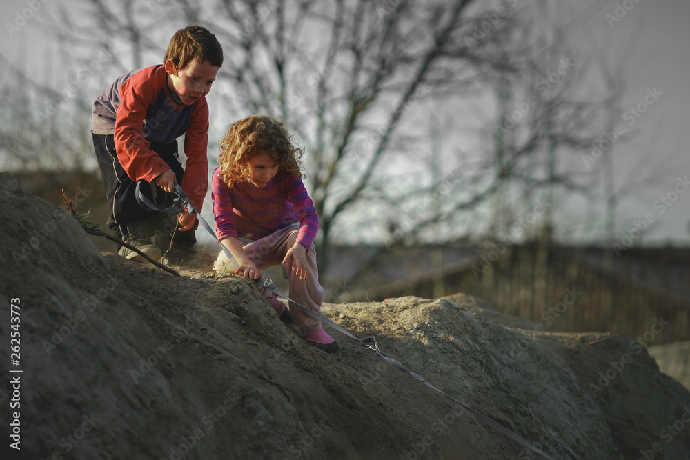Children play on the hill of mud with a dog Children play on the hill of mud with a dog