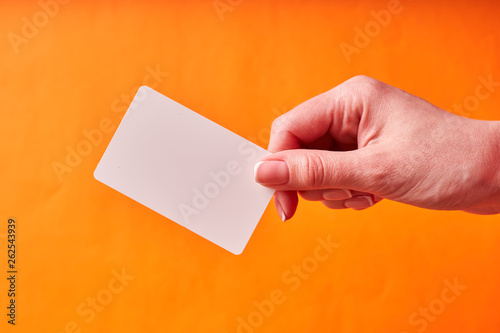 A woman's hand holds a white plastic card. Isolated card in hand