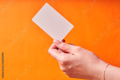 A woman's hand holds a white plastic card. Isolated card in hand