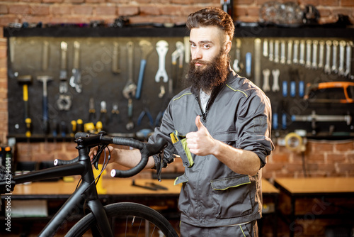 Portrait of a handsome bearded repairman in workwear at the bicycle workshop © rh2010