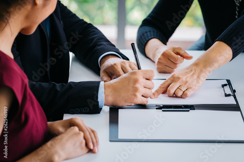 Close-up of married couple signing papers alongside with other witness or agent - can be divorce, law, liability, evidence agreement for marriage