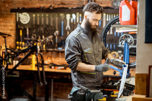 Handsome bearded repairman in workwear working in the beautiful bicycle workshop