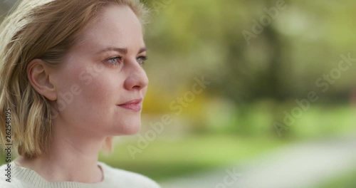 Profile of white womans face with a blurry park in the background