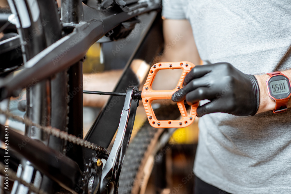 Repairman installing new pedals on a mountain bicycle at the workshop