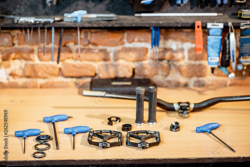 Working place with bicycle parts and working tools on the table of the bicycle workshop