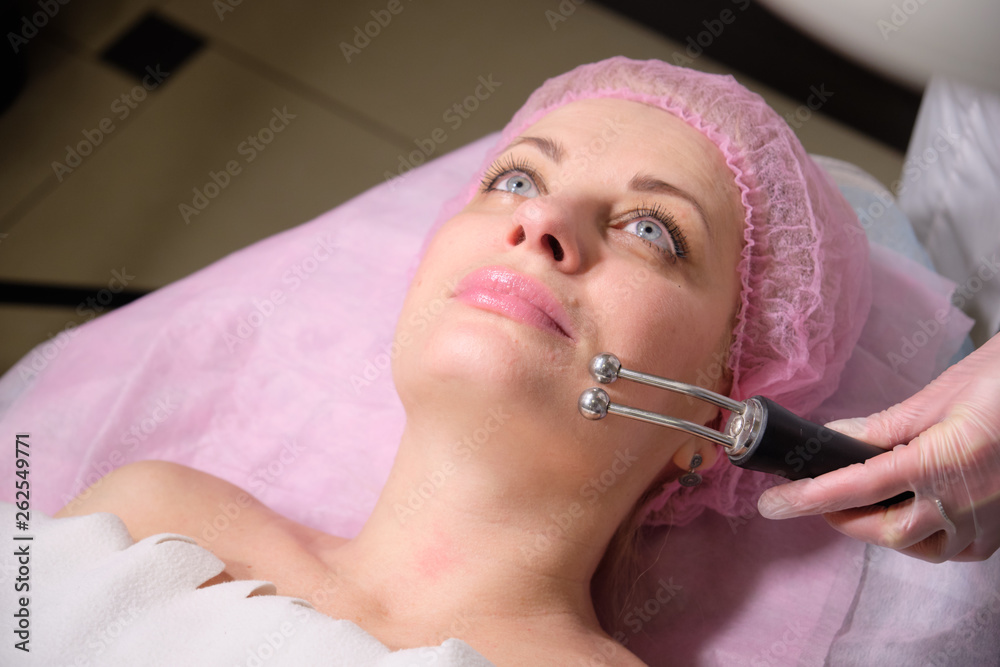 Cosmetologist making hardware procedures for the face  to her patient  . Anti-ageing and smoothing procedure in a beauty salon. Doctor in a cosmetological clinic making a treatment of skin care