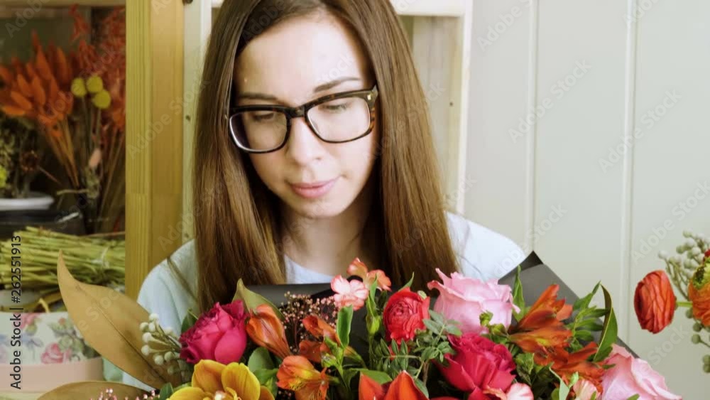 Female florist in flower shop. Woman holding in hands a beautiful and stylish bouquet of fresh flowers in floral design studio. 4K Female florist in flower shop. Woman holding in hands a beautiful and stylish bouquet of fresh flowers in floral design studio. 4K
