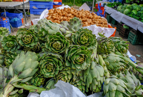 Fresh green artichokes displayed on a market stall.