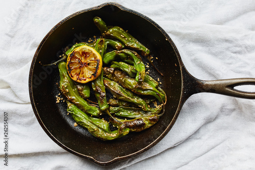 Sesame blistered shishito peppers with lemon, sesame oil and sesame seeds cooked in a cast-iron pan.  (Capsicum annuum var) photo