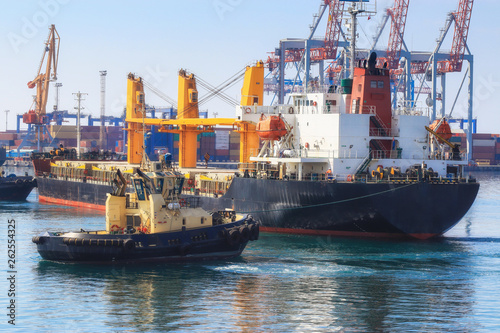 Tugboat assisting Cargo Ship maneuvered into the Port of Odessa, Ukraine. Handling of goods and the work of a commercial port.