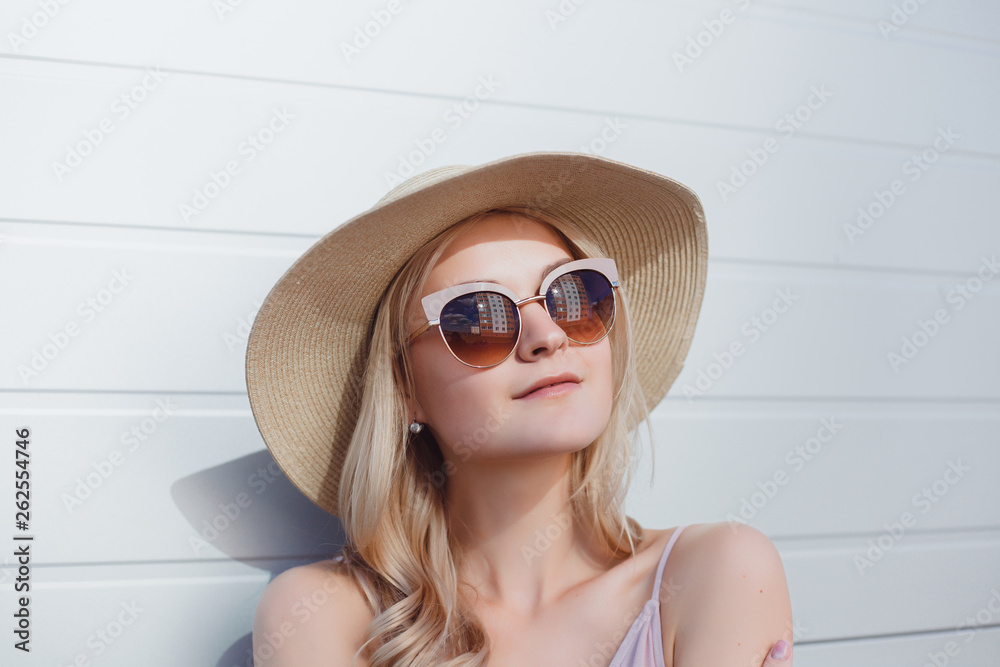 Fototapeta premium Young brunette girl in black standing outside and watching the sunset in the city, the sun shines brightly, fashionable clothes on a girl, hipster style, tattoo, street photo, mood, freedom