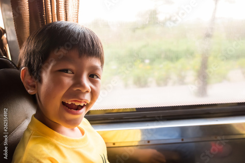 a laughing boy is traveling to the city by the metropolis bus in the morning. he enjoy with this transportation, traffic not jam and good weather.