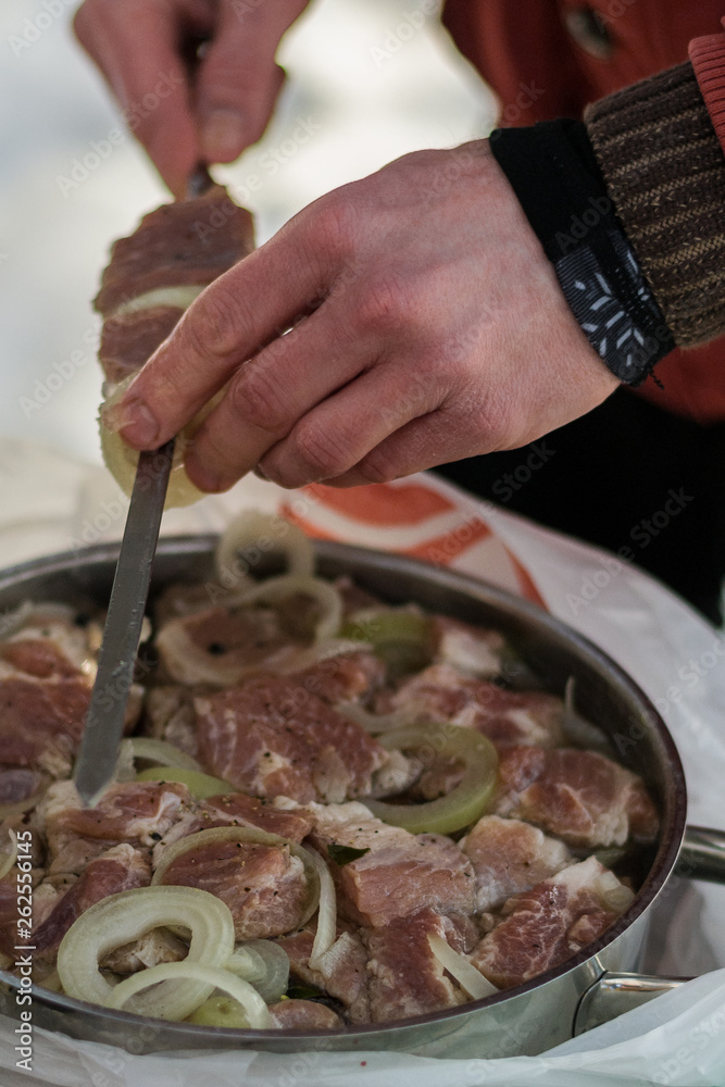 Hand stringing meat on skewers for cooking kebabs