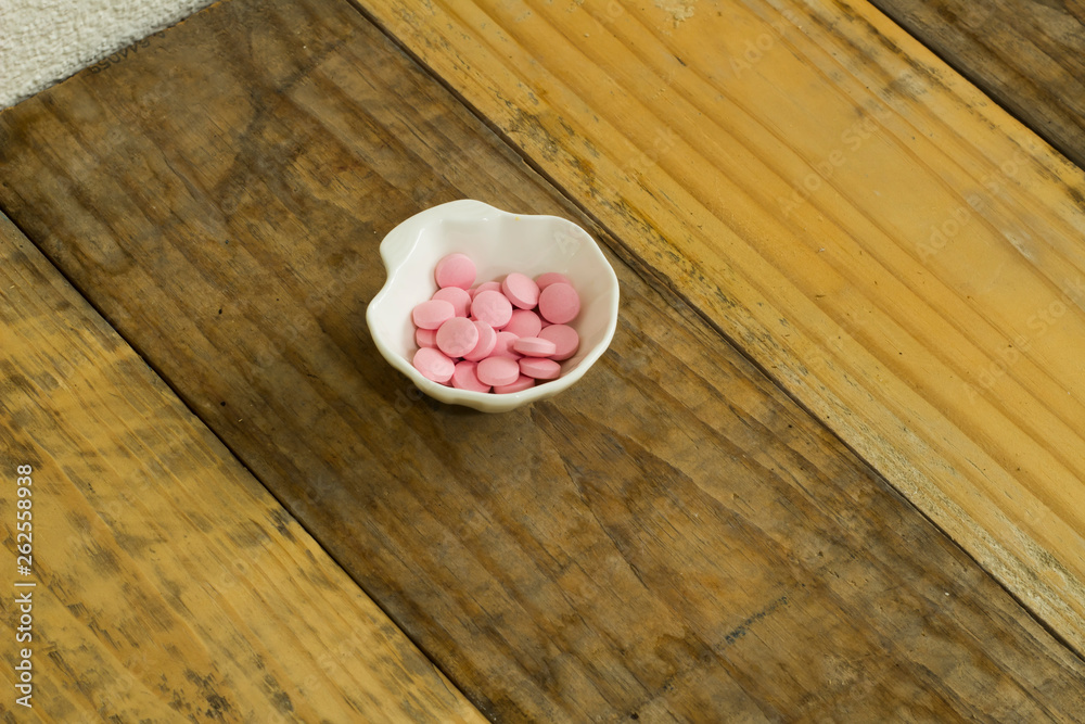Drugs in the form of capsules, tablets and gelatin in oyster-shaped bowls on dirty wooden background Drugs in the form of capsules, tablets and gelatin in oyster-shaped bowls on dirty wooden background