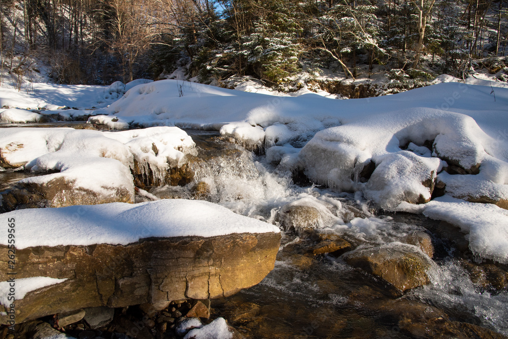 Water flowing in rapids over stone, in the winter mountains Water flowing in rapids over stone, in the winter mountains