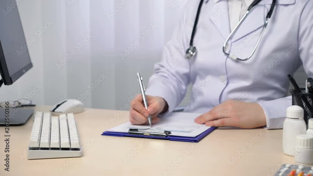 Female physician writing a report, taking notes, filling out papers in office. Healthcare and medicine