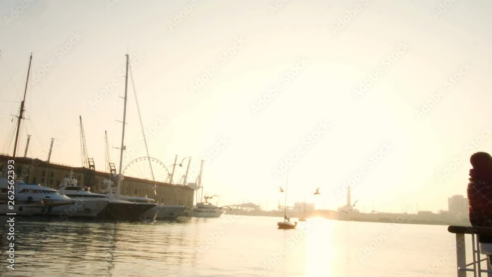sailboat at sunset in the ancient port of Genoa, seagulls flying in the sky sailboat at sunset in the ancient port of Genoa, seagulls flying in the sky