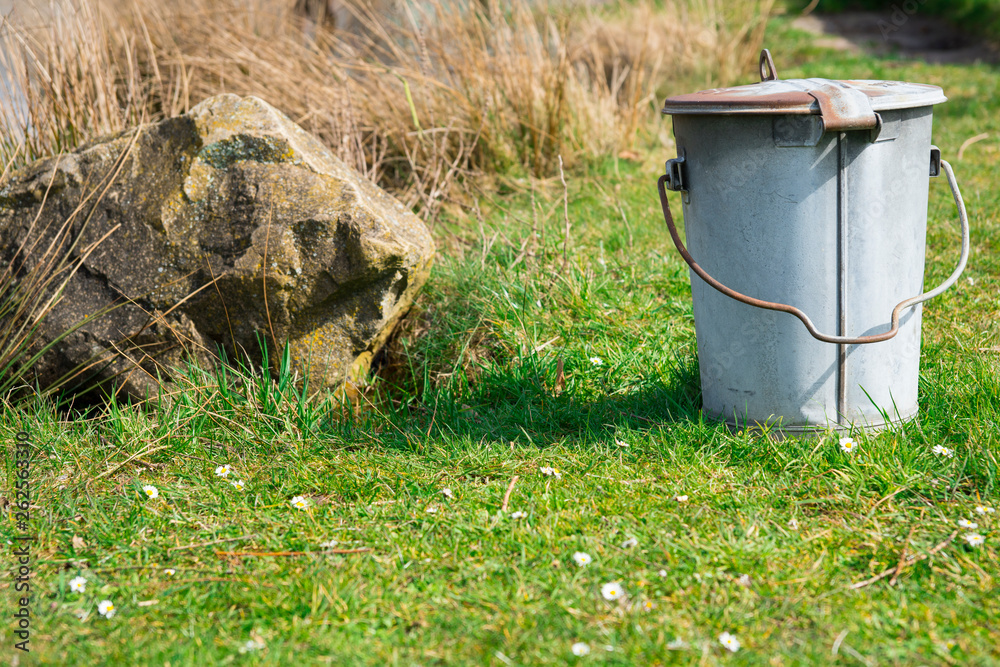 metal trash bin, bucket on green grass field metal trash bin, bucket on green grass field