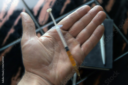 syringe in a person s hand  on a notepad background  short focus  toning